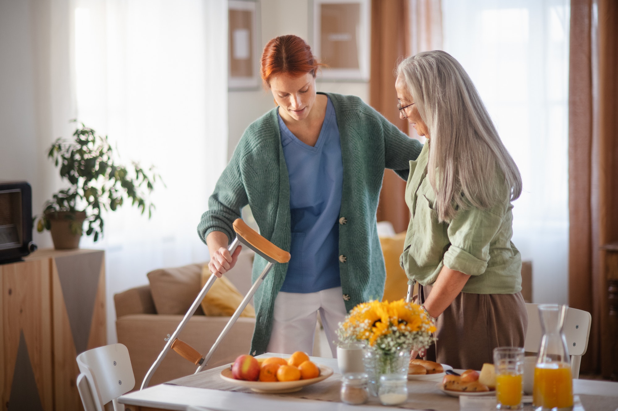 Nurse helping senior woman with walking after leg injury.